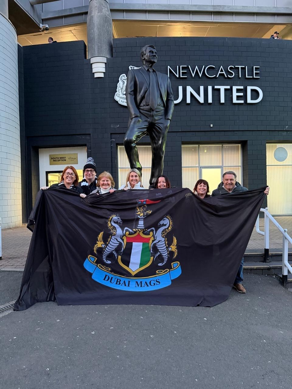 Dubai Mags fans holding club flag outside St James' Park