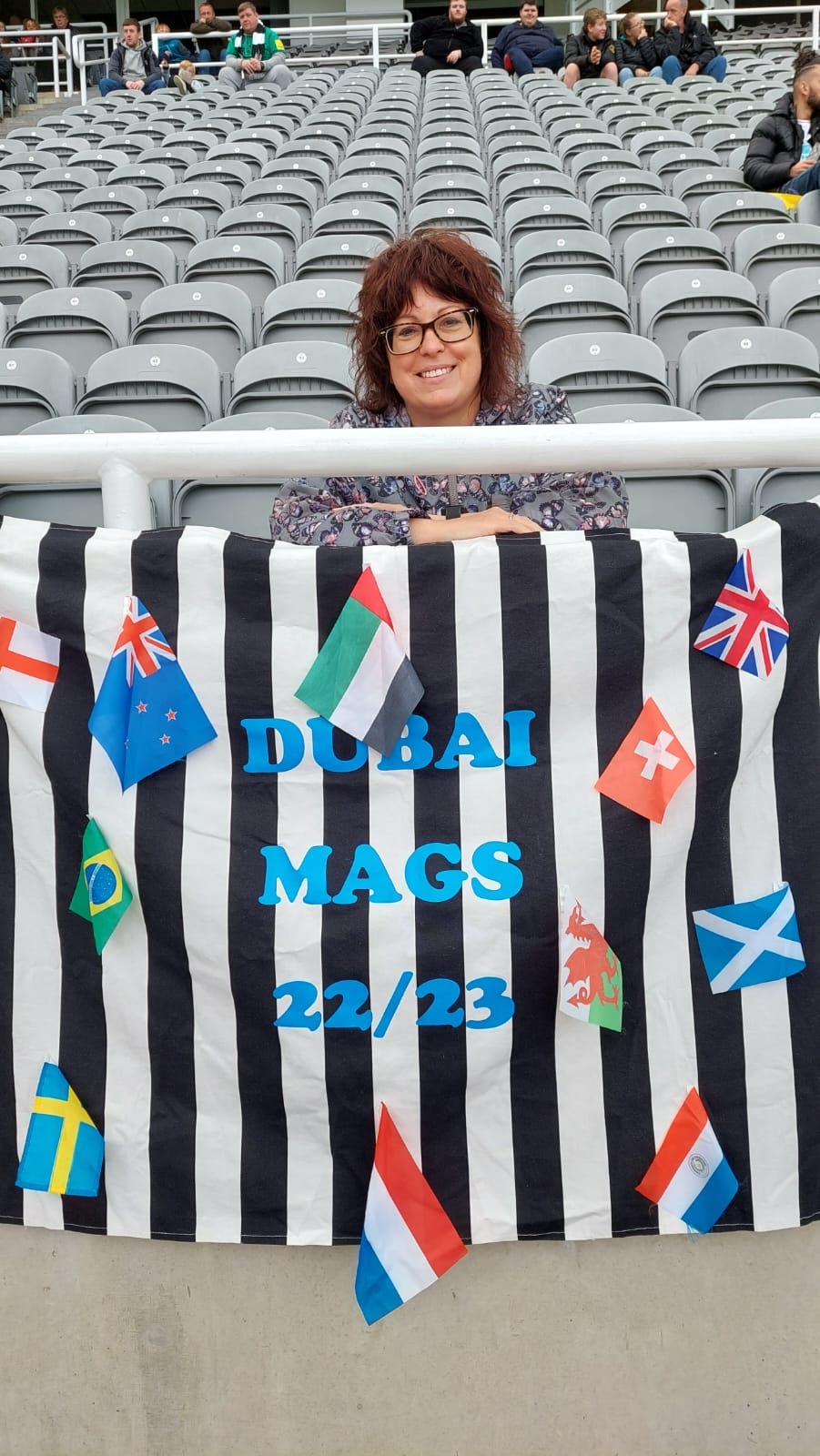 Julie Roseblade holding the Dubai Mags flag at St James' Park